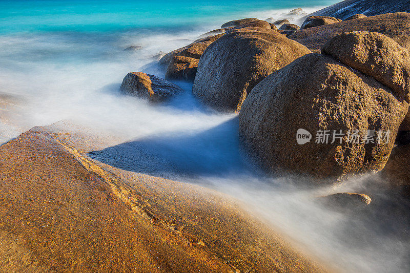 慢快门海岸场景，海水蓝色的海浪轻轻地冲刷着岩石