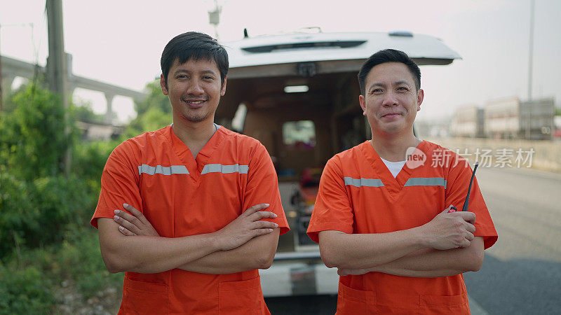 两个护理人员的肖像。两个穿着制服的亚洲医护人员双手交叉站在救护车后面，对着镜头微笑。EMS护理人员