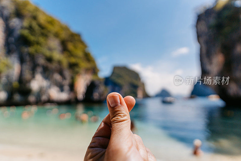 一个年轻人在泰国洪岛的海滩上做着手指心形的动作