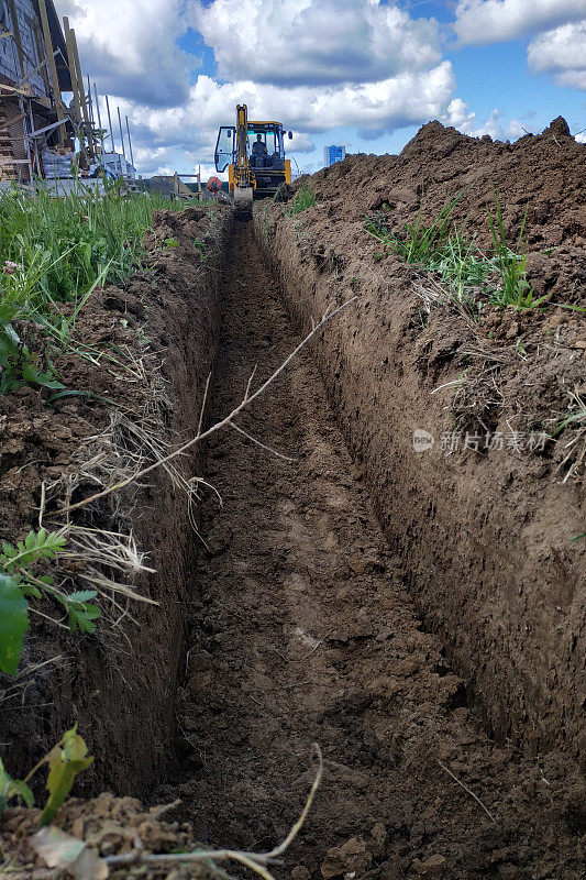 在挖好的沟渠上布线电缆，为地面上的房屋供电。