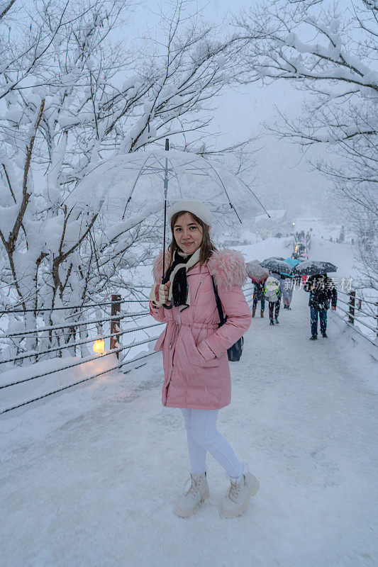 美丽的女游客享受他们的旅行白川古村在日本的冬天厚雪