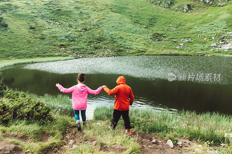 年轻夫妇在美丽的湖附近的山上玩耍