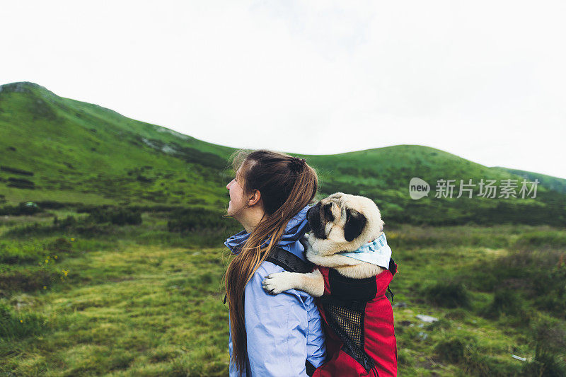 女人和狗在背包里登山