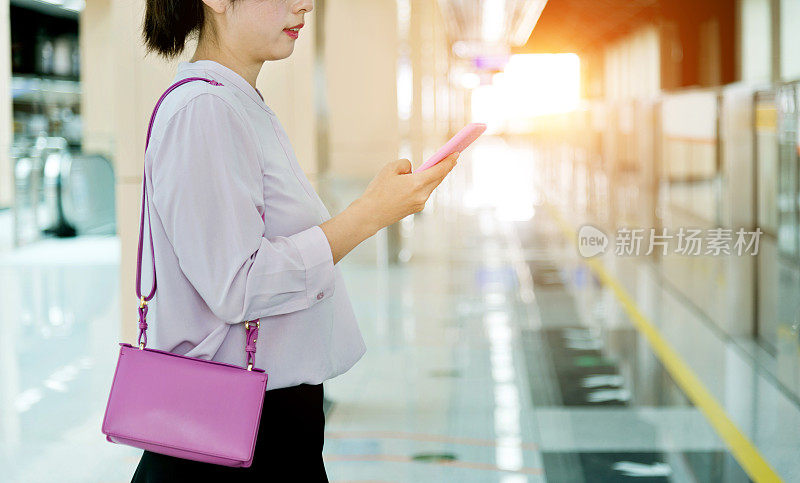 一名女子在地铁站使用智能手机