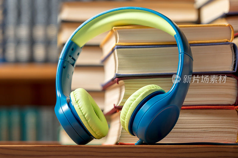 有声书概念-耳机与书堆在图书馆