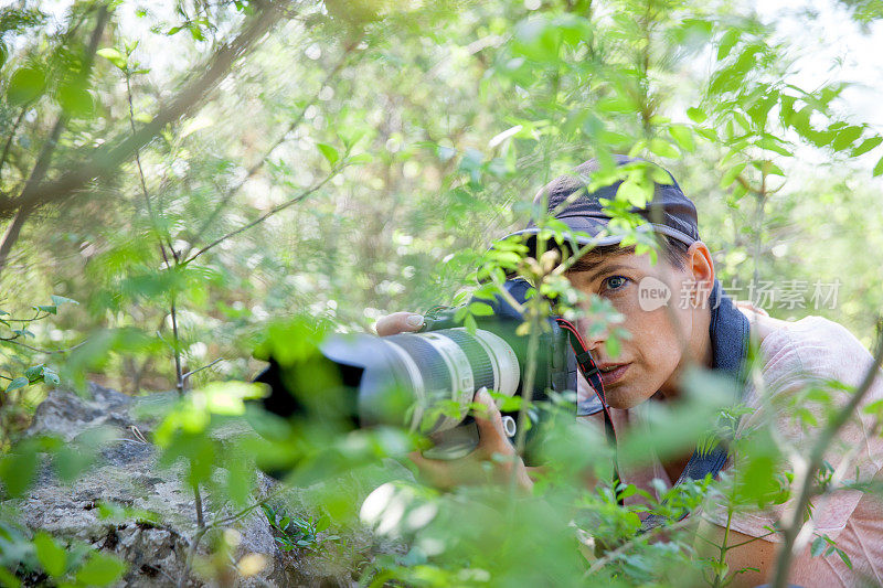 在灌木丛中等待的野生动物摄影师