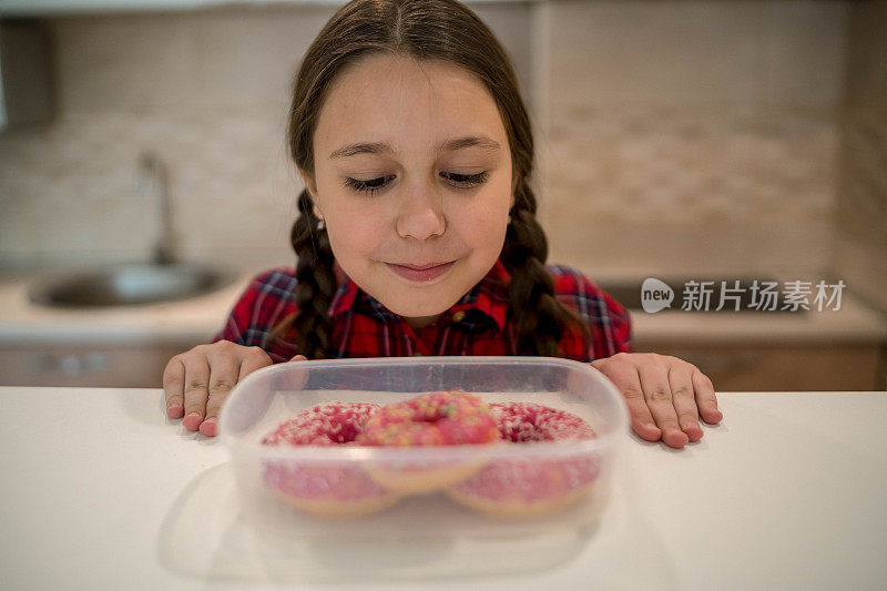 对孩子的饮食。悲伤和不快乐的孩子触及甜甜圈。孩子们的美味食物。孩子在看甜甜圈。垃圾食品上瘾。