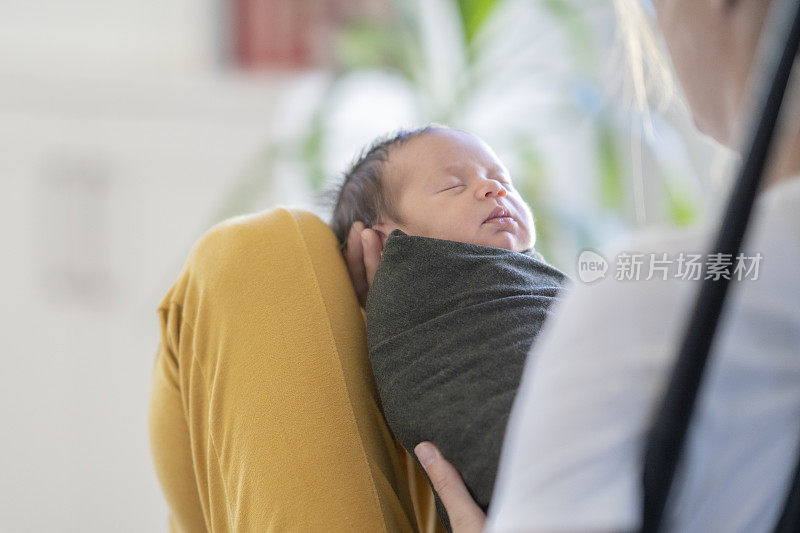 白人母亲抱着襁褓中的新生儿