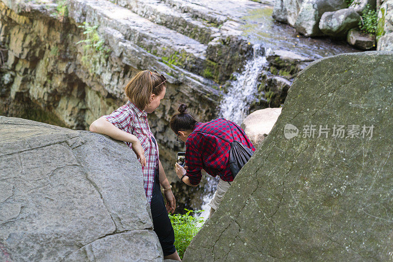 在一个阳光明媚的夏天，两个十几岁的女孩在宾夕法尼亚州上黑涡流的森林里探索丁岩瀑布