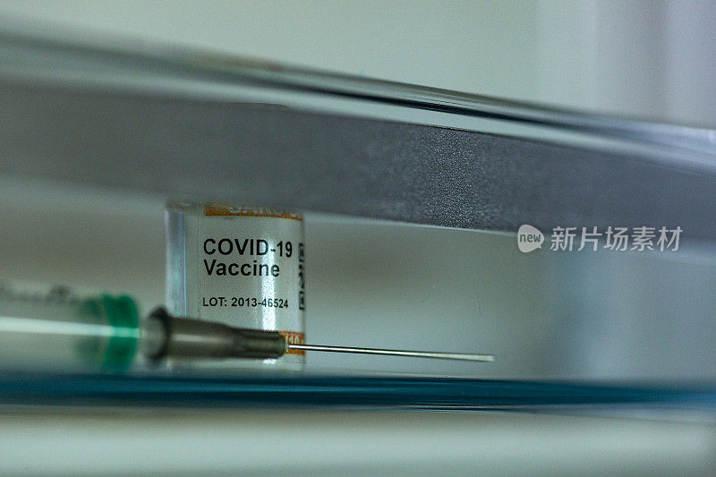 低温保存的COVID-19疫苗瓶。标记SARS-CoV-2对抗冠状病毒。注射器的细节在前景。