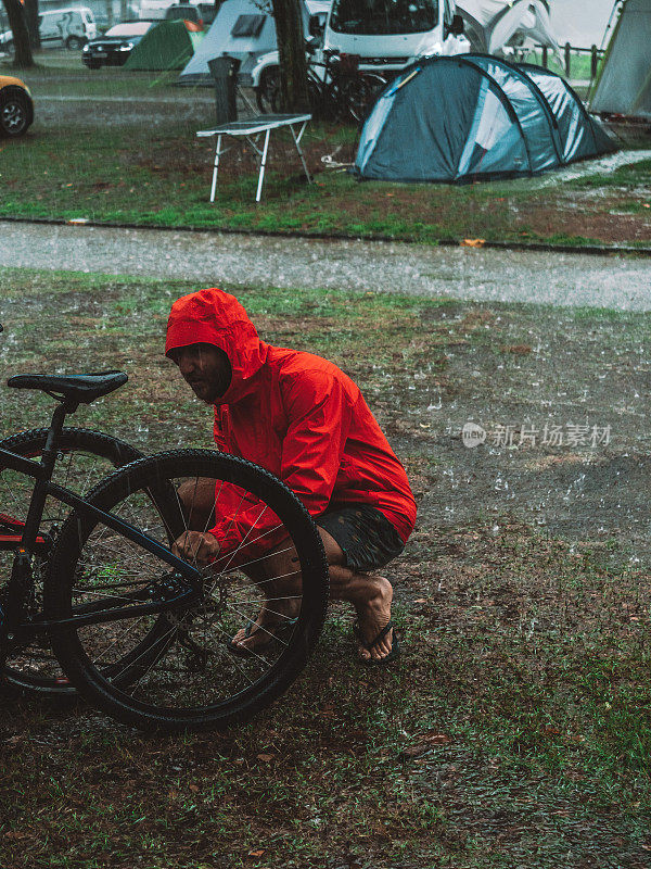 一名男子在暴雨中修理山地车