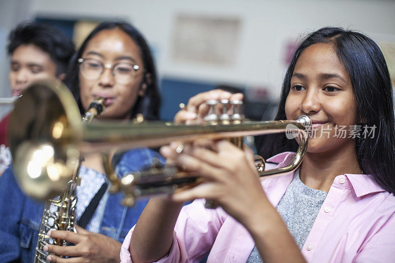 十几岁的亚洲混血女孩在学校的音乐课上吹小号