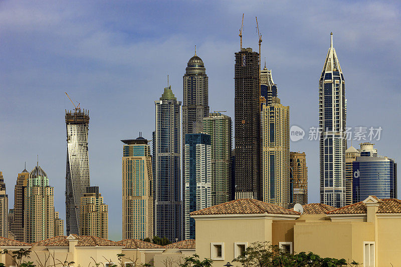 迪拜，阿拉伯联合酋长国-在一些草甸别墅的屋顶上迪拜码头摩天大楼的侧视图;一些塔正在建设中。