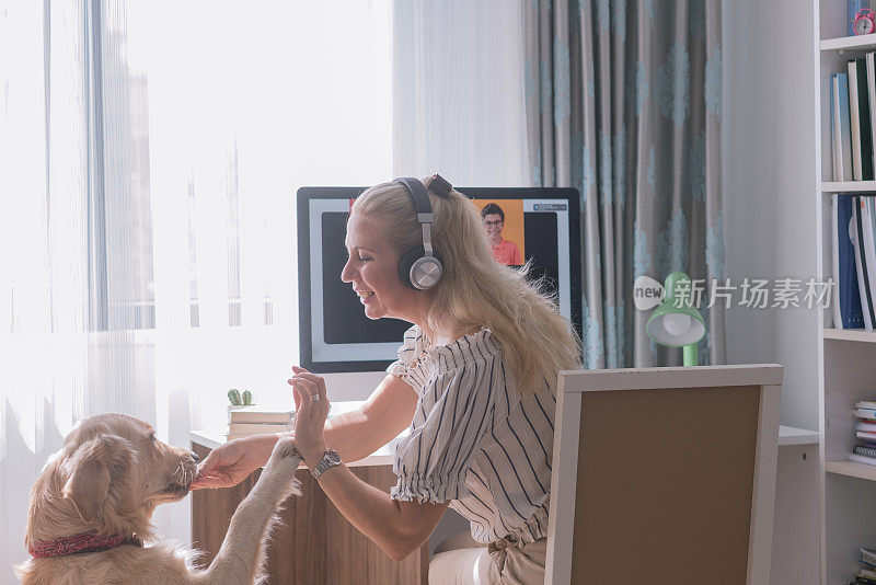 一位妇女和她的家人和狗在电脑前召开电话会议。