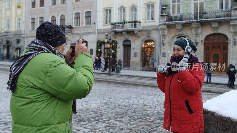 老年夫妇游客奶奶爷爷在冬城用复古相机拍照
