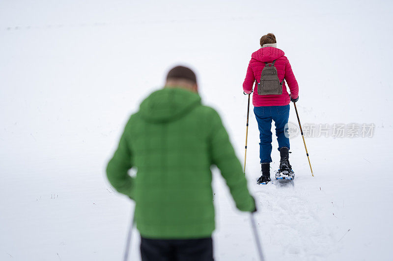 老年人穿着雪鞋在雪地里行走，保持社交距离