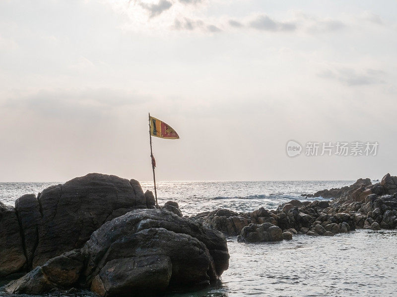日落时斯里兰卡国旗在岩石上的海景，戏剧性的天空。没有人旅行