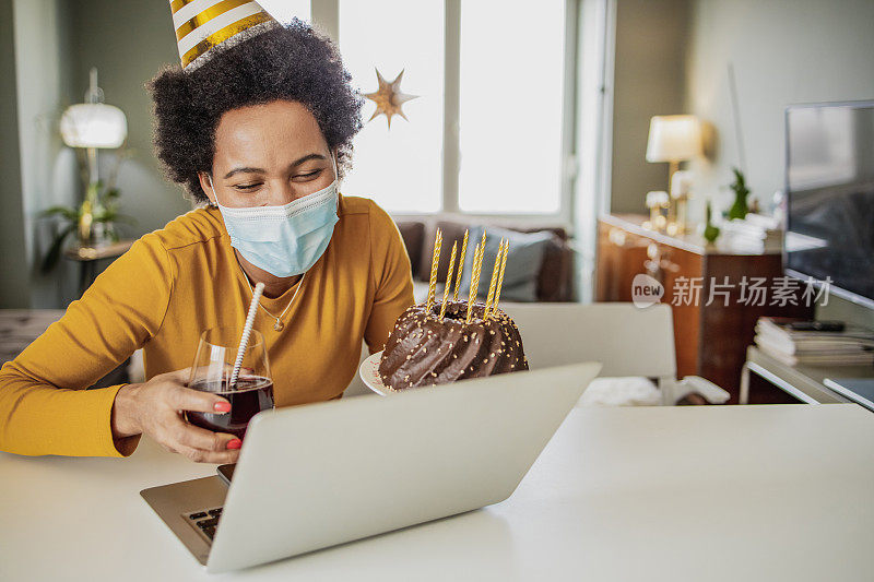 一位戴着面具的非洲妇女在视频通话中庆祝生日