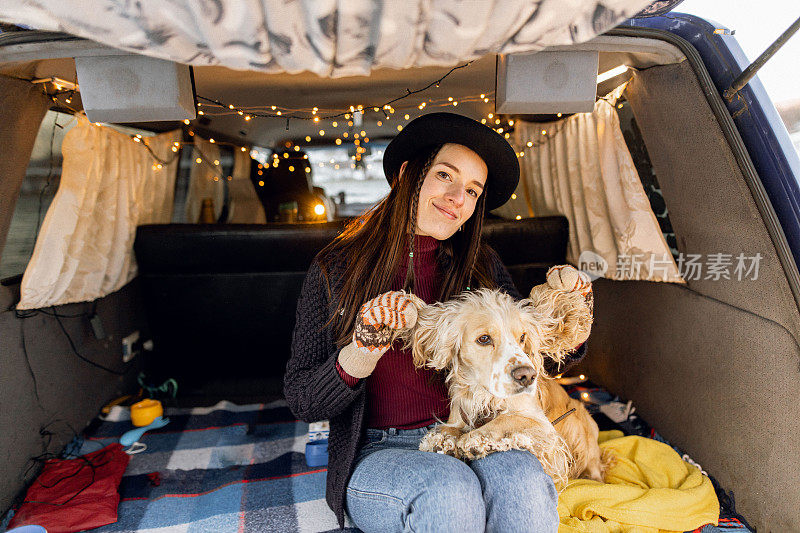 年轻时髦的女人在一辆旧货车里拥抱漂亮的西班牙猎犬