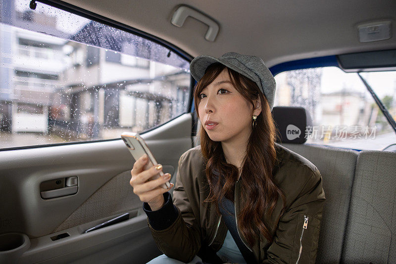 年轻女子坐在车里，用智能手机查看地图