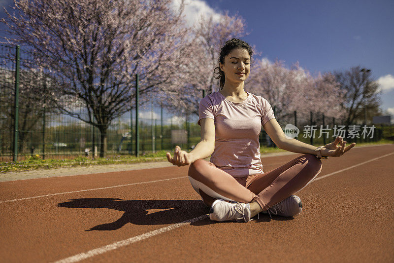 运动的年轻女子在跑道上做瑜伽。