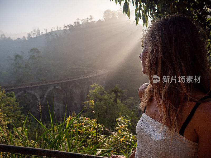 女游客在日落时凝视着著名的大桥