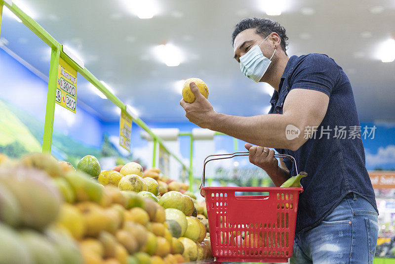 拉丁裔男性在杂货店购物时戴着面具