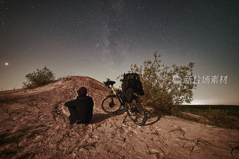 骑着电动车的人在月光下仰望星空