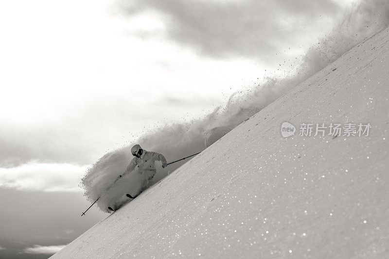 偏远地区的滑雪者从雪山山脊上滑下来