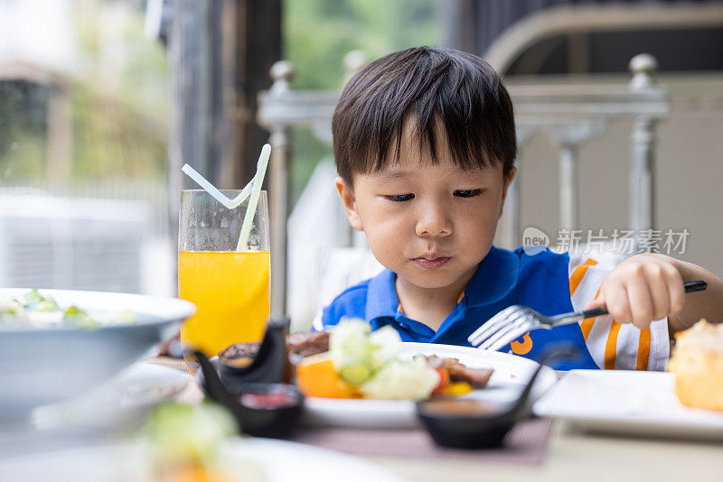 一个小男孩在餐馆里吃牛排