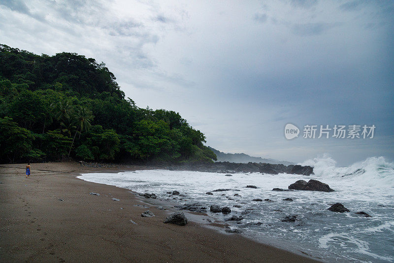 一个女人在多岩石的海岸线上