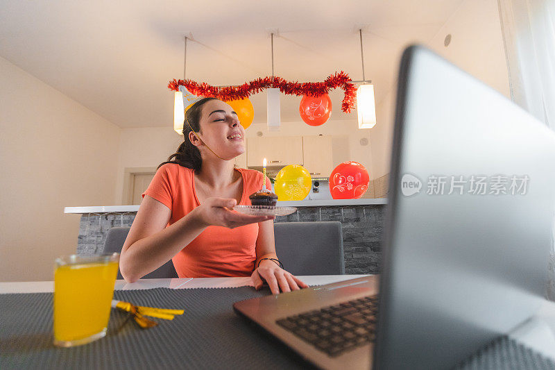 一个年轻的女人在家里庆祝生日与她的朋友在视频电话她的笔记本电脑由于封锁