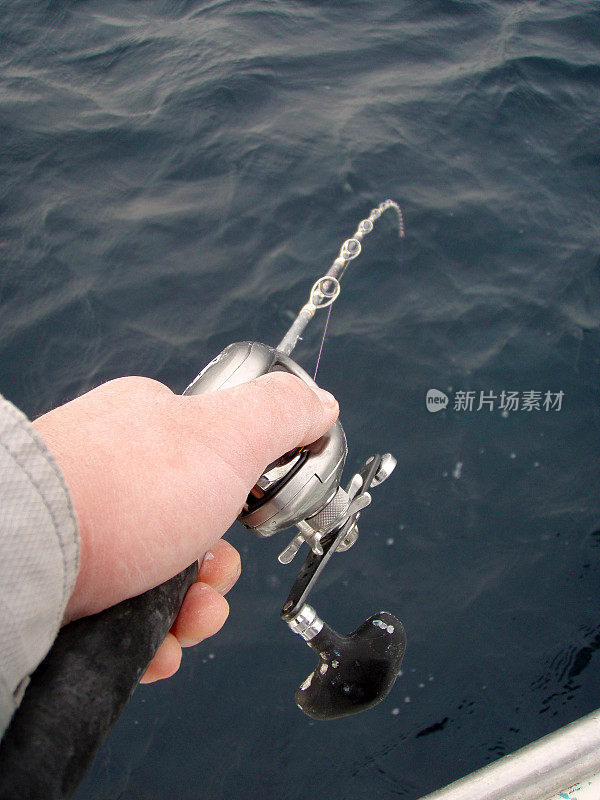手里拿着鱼饵卷轴和鱼竿，勘探难以捕获的目标鱼。“咬，从船甲板上。
