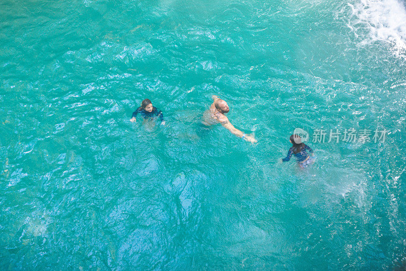 家庭游泳在与世隔绝的自然瀑布泻湖在热带天堂