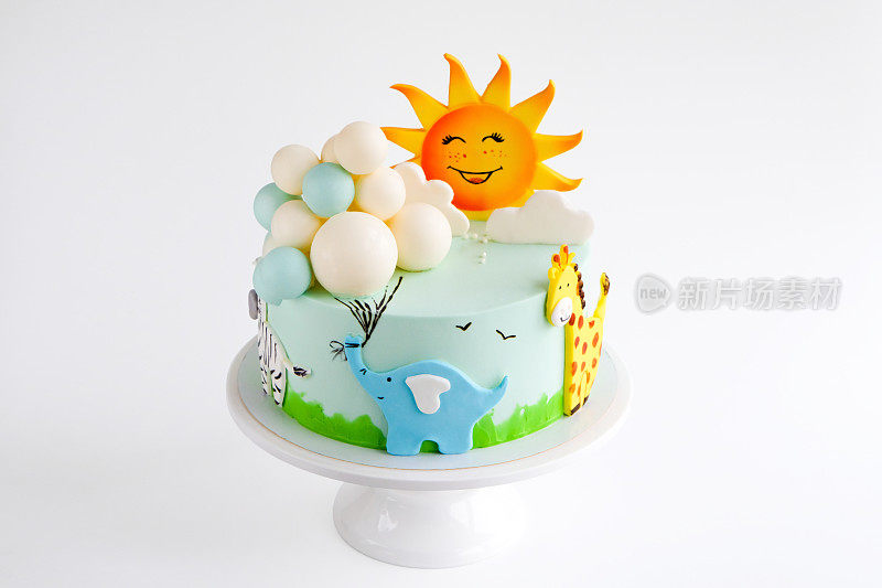 用太阳、云彩、大象、长颈鹿、斑马动物雕像和气球装饰的婴儿生日蛋糕。