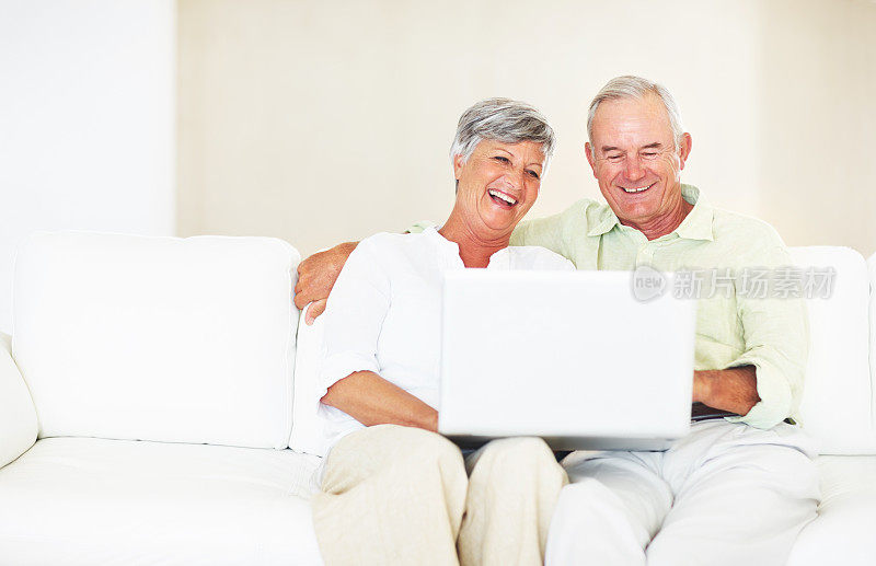成熟的夫妇在沙发上使用笔记本电脑