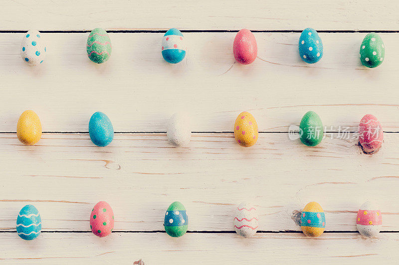 五彩缤纷的复活节彩蛋和手绘在木制背景上