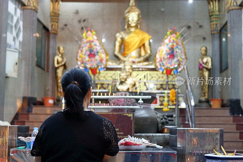 泰国妇女在寺庙祈祷佛的后视图