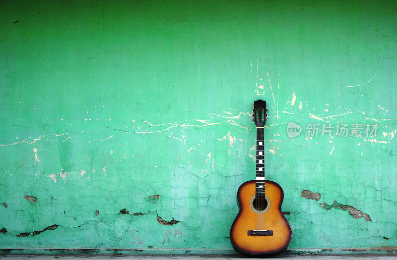 旧的绿色墙上挂着西班牙吉他