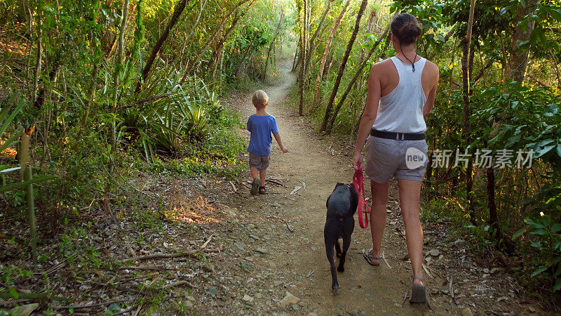 母亲和孩子徒步旅行和遛狗在热带森林小径