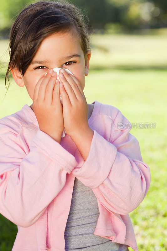 年轻女孩用纸巾擤鼻子