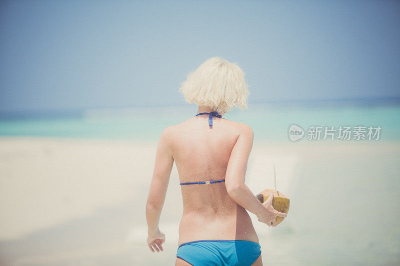 马尔代夫，一个女人带着椰子在海洋中奔跑