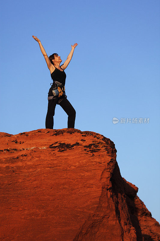 一位女性攀岩者在日落前到达了山顶