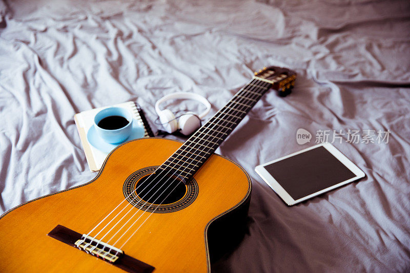 床上放着吉他和咖啡杯