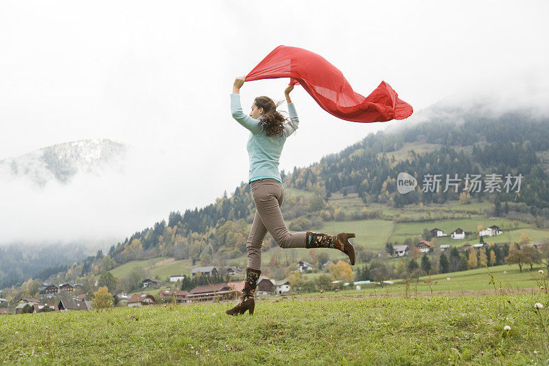 拿着红围巾在山上跑下山的女人