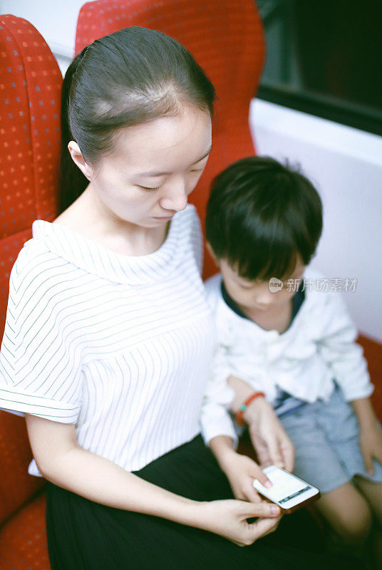 快乐的亚洲母亲和儿子使用智能手机