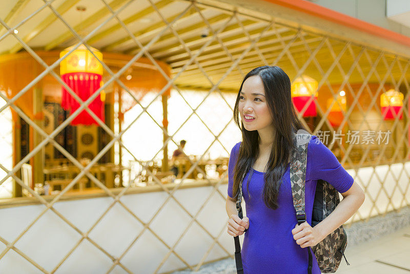 迷人的长发亚洲女人走过一家餐厅