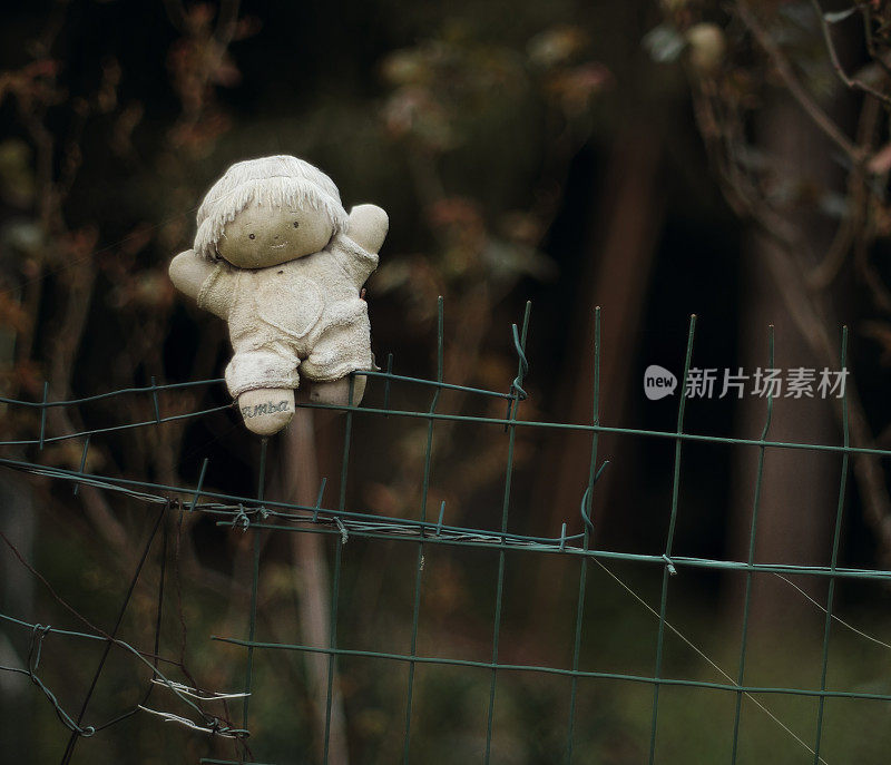 小女孩娃娃稻草人被钉在花园篱笆上