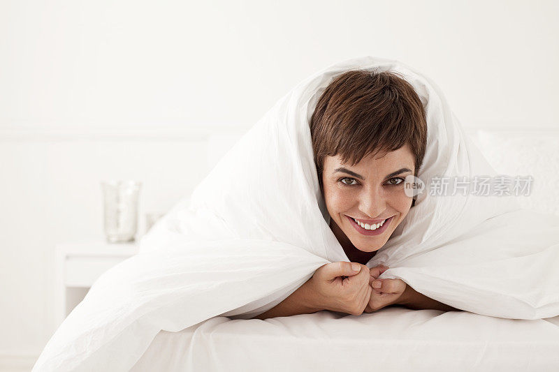 年轻女子在床罩下，头向外窥视