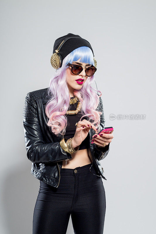 蓝粉色头发的无忧无虑的女孩穿着皮夹克在手机上发短信